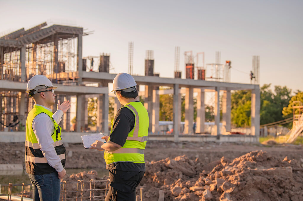 Two Asian engineer working at site of a large building project,Thailand people,Work overtime at construction site,Team of engineer discus at site